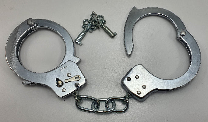 Metallic handcuffs with a key on a gray background