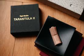 Vape pen in a black box with 'Your Smoke Tarantula II' branding on a wooden surface.