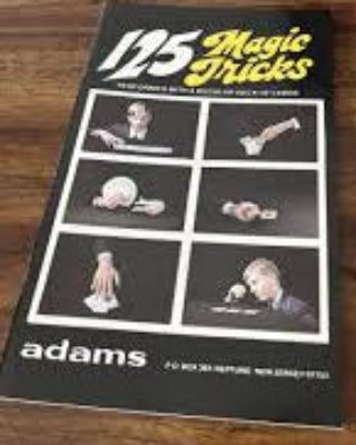Book titled '195 Music Tricks' by Adams on a wooden surface with other items.