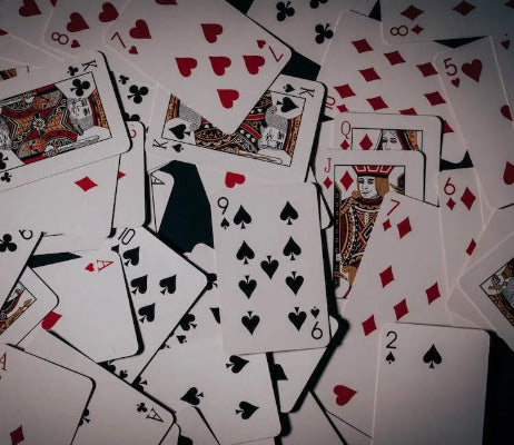 Scattered playing cards with various suits and values on a white background