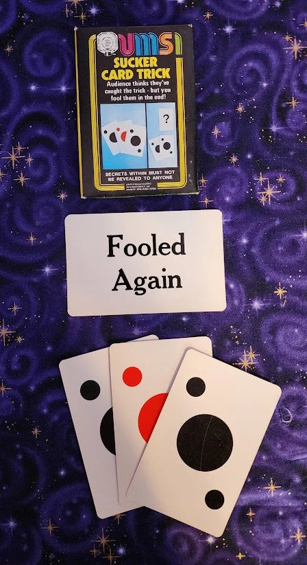 Card trick with cards and a box labeled 'Slicker Card Trick' on a purple swirling background.
