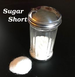 Glass container of sugar with a scoop on a black background