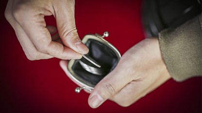 Close-up of hands opening a small purse on a red background