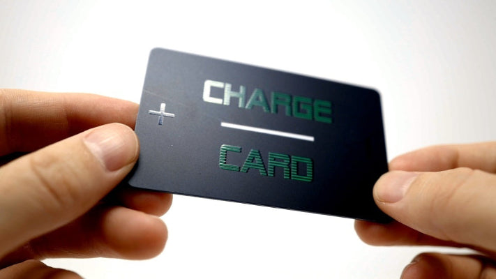 Person holding a black card with 'Charge Card' text on a white background