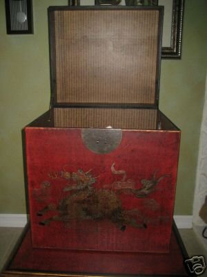 Decorative wooden box with a red top featuring dragons on a green wall background
