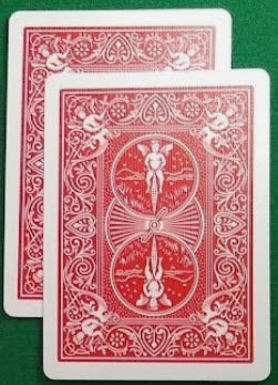 Two red playing cards with intricate designs on a green background