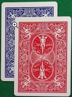 Two playing cards, one red and one blue, on a green surface.