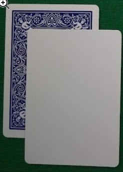 Two playing cards on a green surface, one with blue decorative border and text, the other plain.