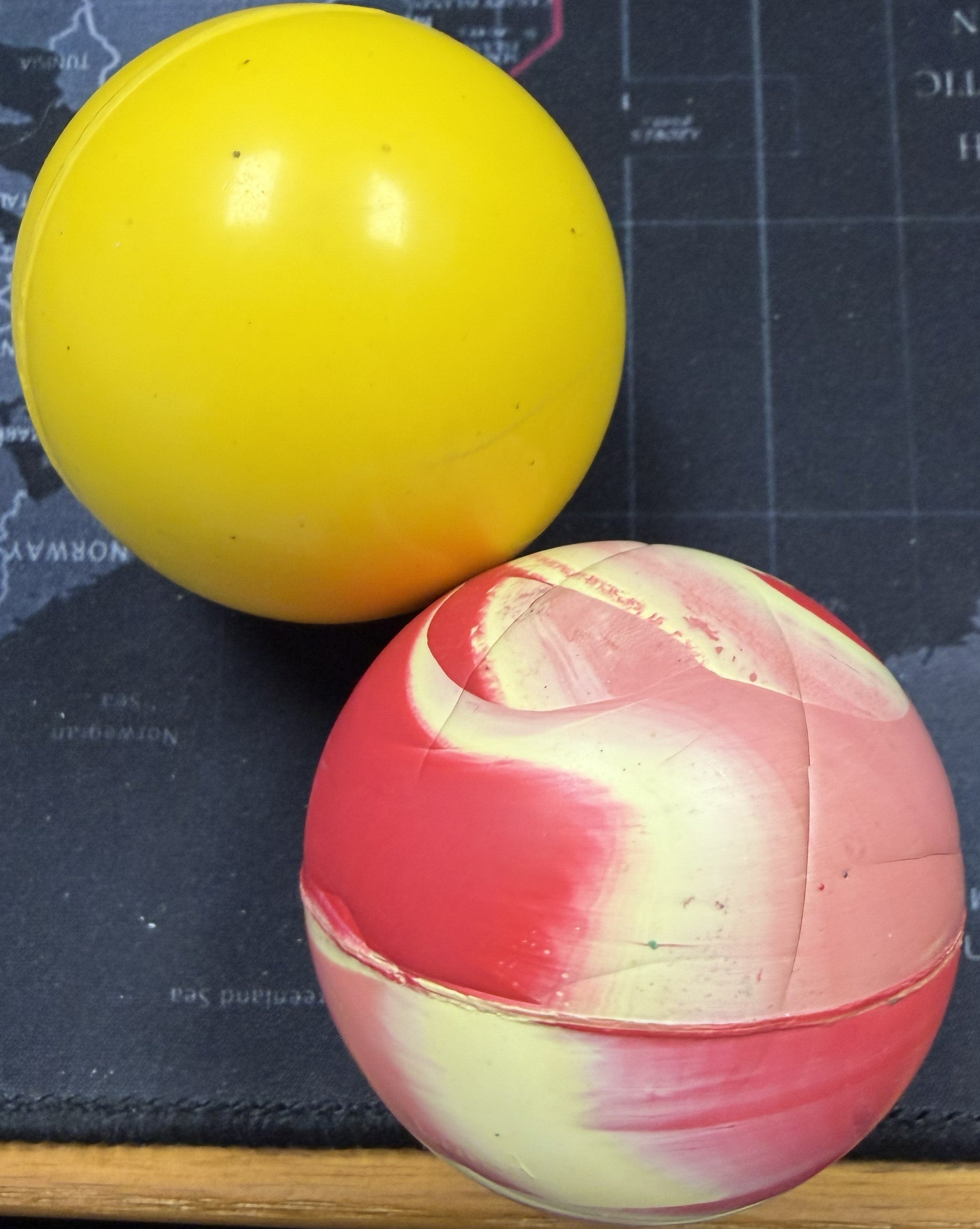 Yellow and red and white striped balls on a dark textured surface