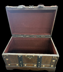 Open vintage-style wooden trunk with metal accents on a cluttered background
