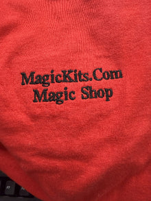 Red fabric with 'MagicKits.com Magic Shop' text embroidered on it.