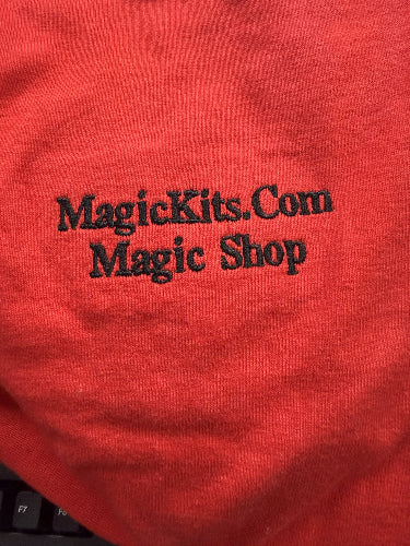 Red fabric with 'MagicKits.com Magic Shop' text embroidered on it.