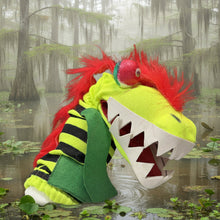 Colorful sock monster with a red mohawk and angry face on a dark surface