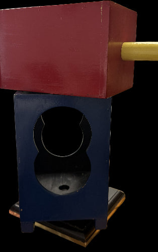 Red and blue wooden block with a circular hole on a wooden surface