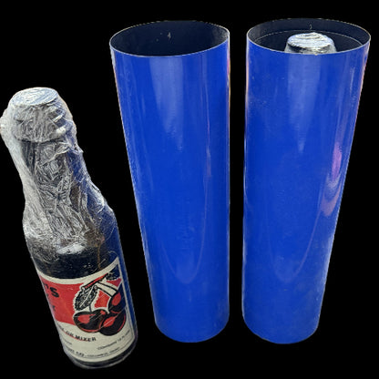 Two blue rolls of vinyl wrap next to a bottle with cellophane on a cluttered surface.
