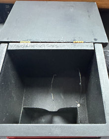 Black metal box with a slot on a wooden surface
