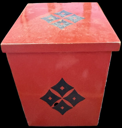 Red box with black geometric design on a dark surface