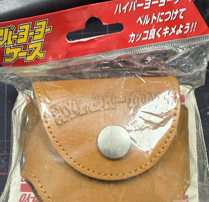 Brown leather pouch with a button in clear packaging on a red background with Japanese text.