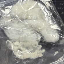 White powdery substance in a clear plastic bag on a dark surface with text