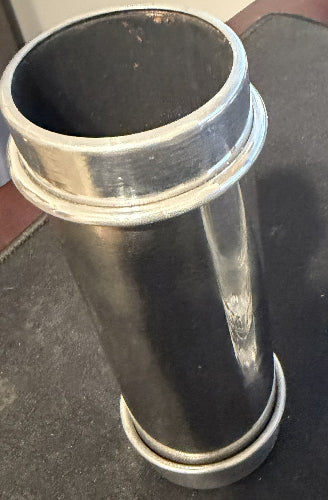 Metal cocktail shaker and clear glass on a dark surface