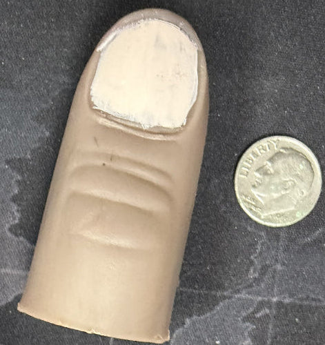 Artificial finger with a coin for scale on a textured surface