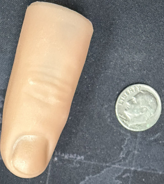 Artificial finger next to a coin on a dark textured surface