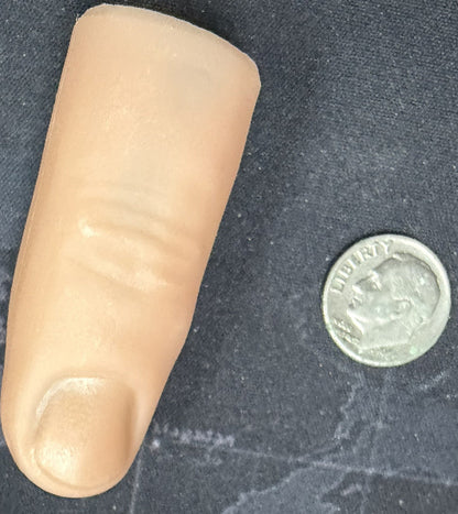 Artificial finger next to a coin on a dark textured surface