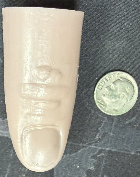 Prosthetic finger next to a coin on a textured surface