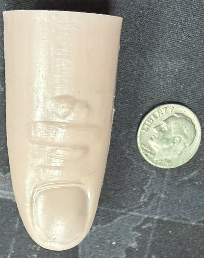 Prosthetic finger next to a coin on a textured surface