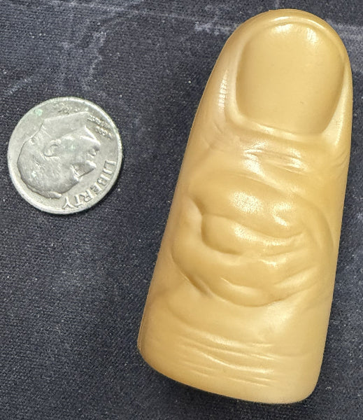 Large beige plastic finger next to a quarter on a dark textured background