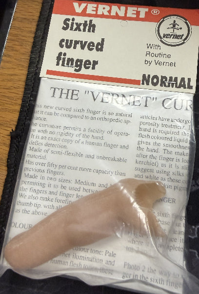 Plastic model of a sixth curved finger with Vernet packaging on a wooden surface