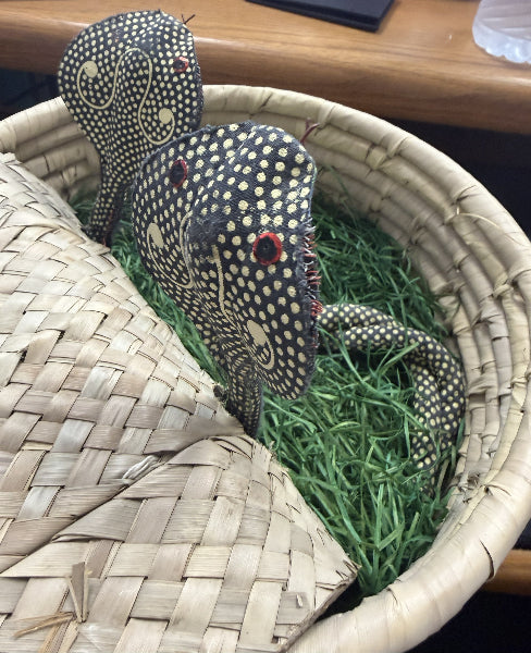 Decorative lizard toy on grass inside a woven basket