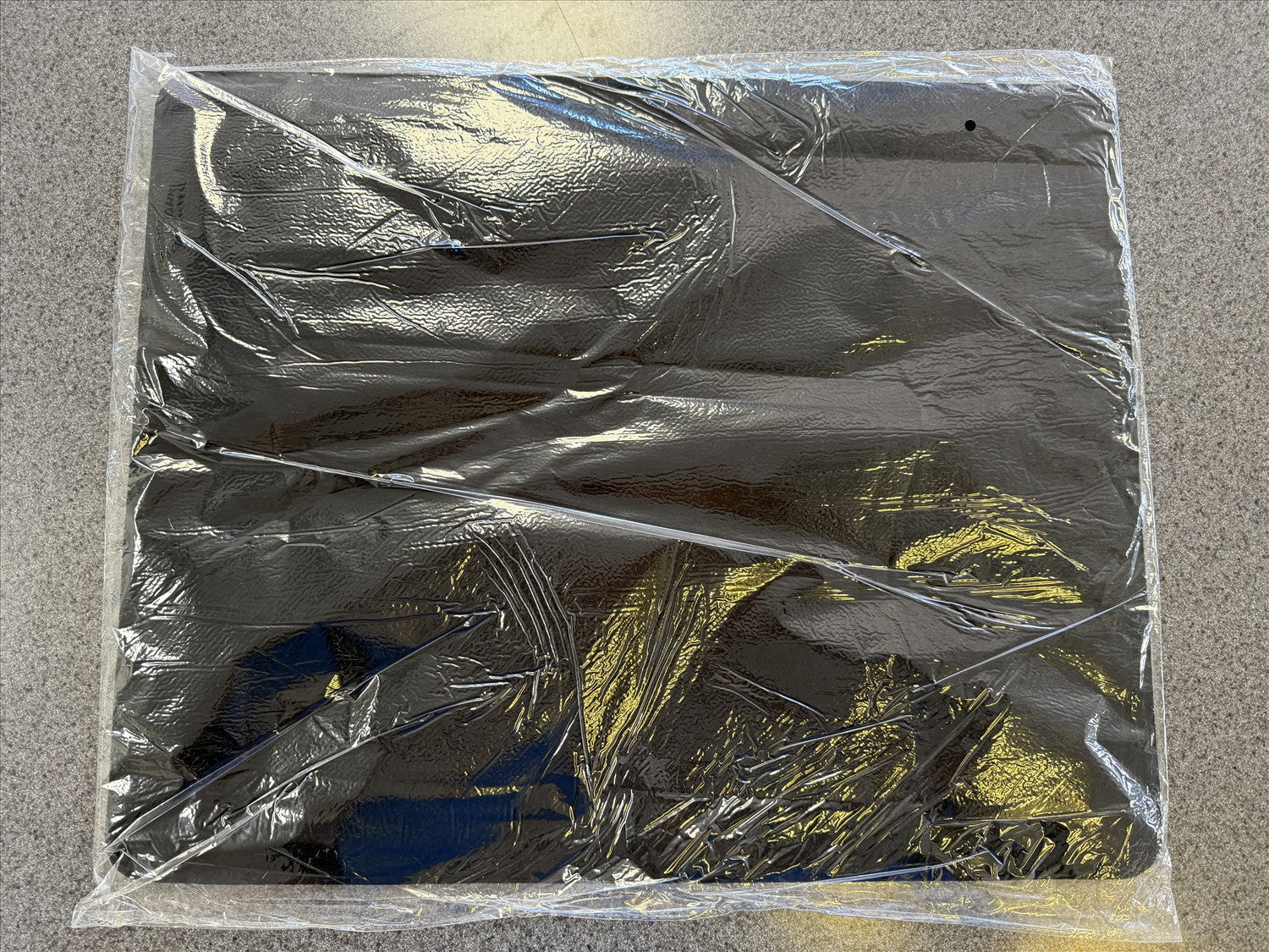 Clear plastic wrap covering a rectangular object on a gray surface