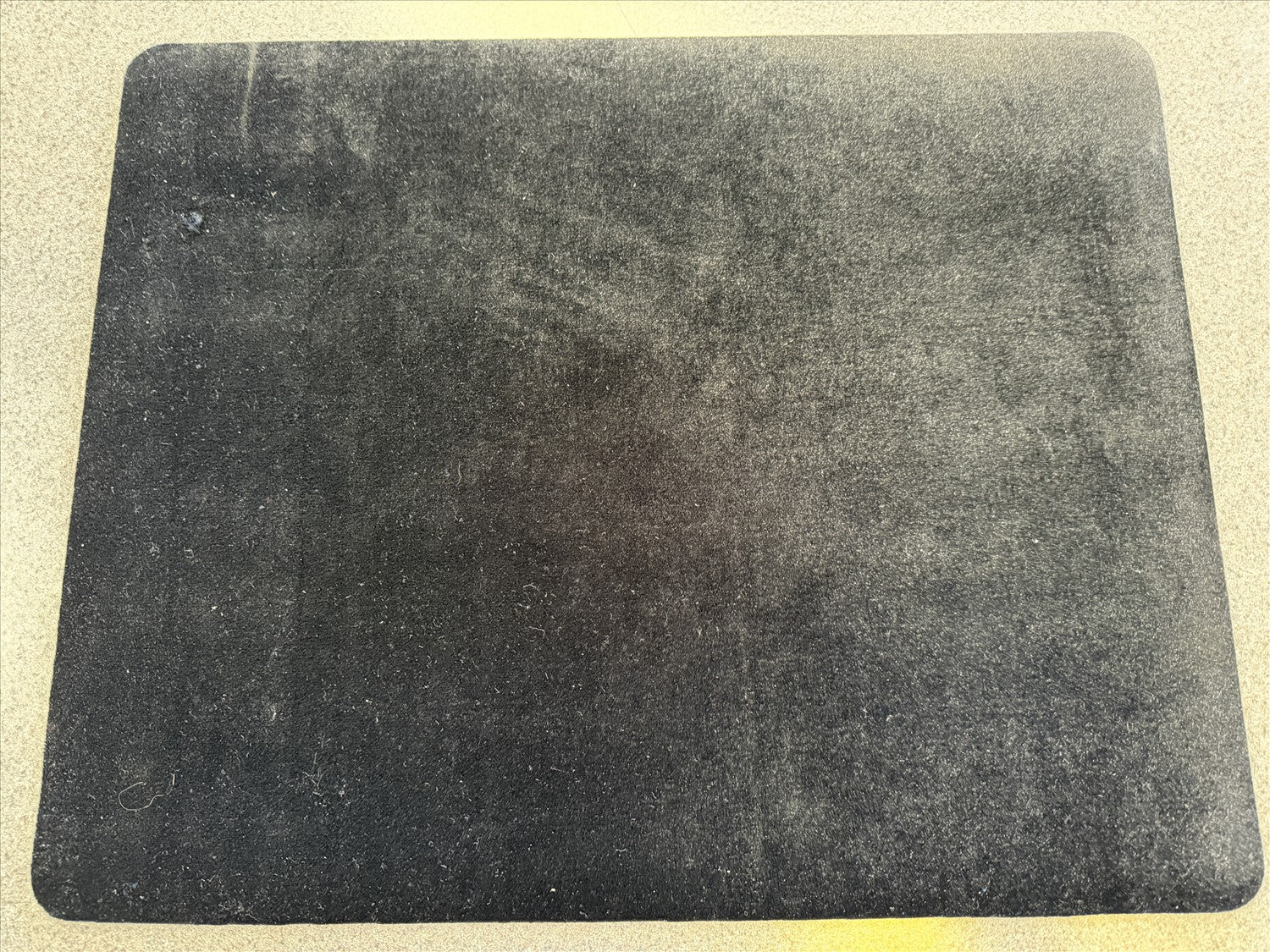 Dark gray mouse pad on a light beige surface