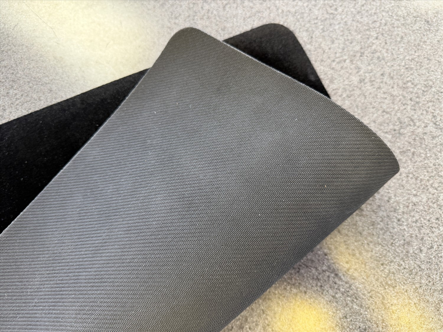 Two pieces of black fabric on a textured surface