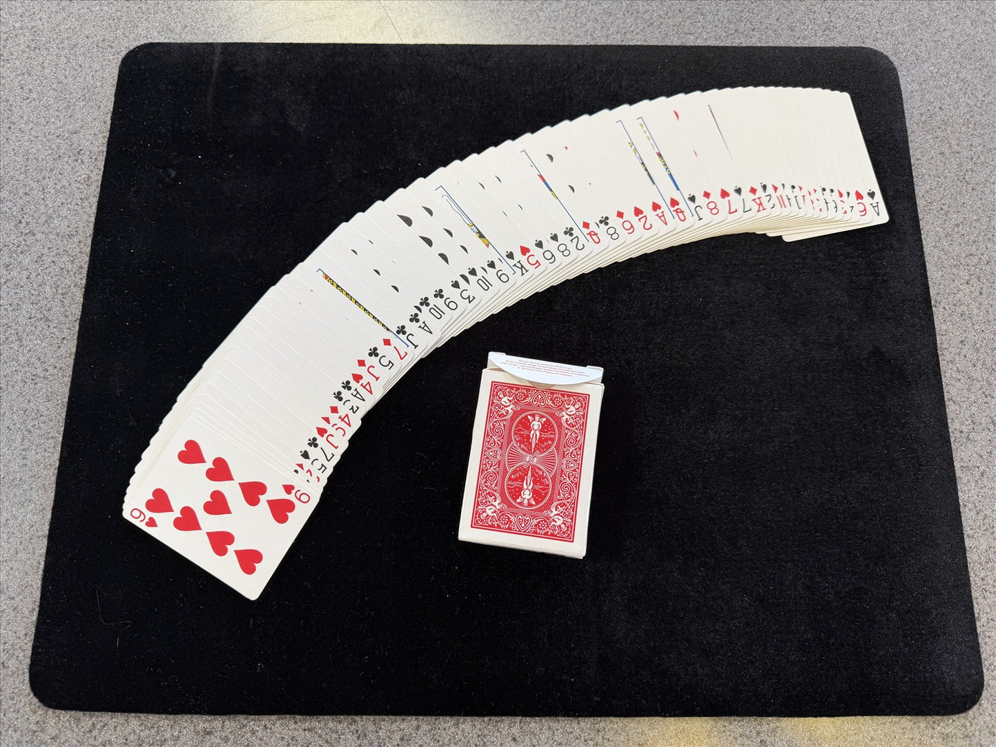Playing cards fanned out on a black surface with a red card at the bottom.