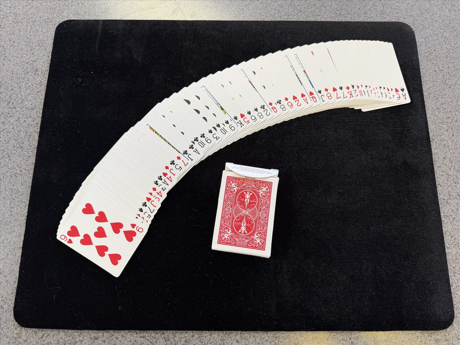 Playing cards fanned out on a black surface with a red card at the bottom.