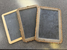 Three vintage slate slates with wooden frames on a gray surface