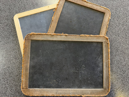 Three vintage-style blackboards with wooden frames on a textured surface