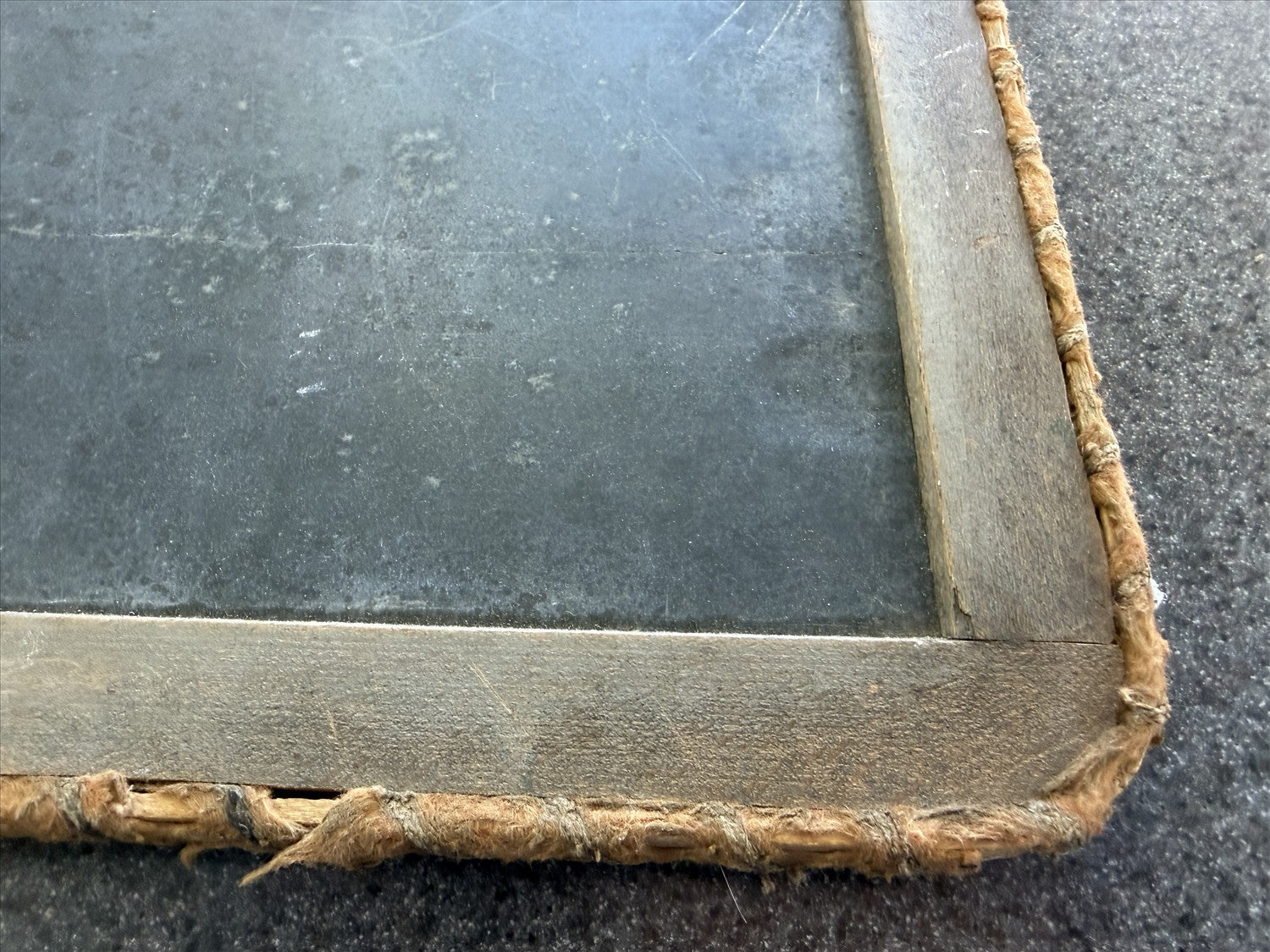 Corner of an old book with worn leather binding on a dark surface