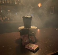 Black coffee filter, white coffee filter, playing cards, and a small book on a gray surface.