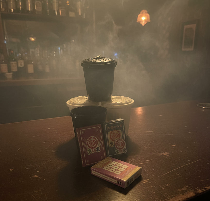 Black coffee filter, white coffee filter, playing cards, and a small book on a gray surface.