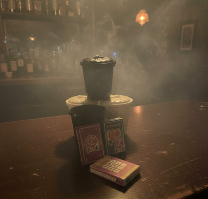 Black coffee filter, white coffee filter, playing cards, and a small book on a gray surface.