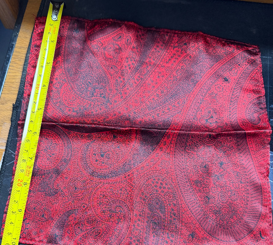 Red paisley fabric with a measuring tape on a black surface