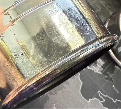 Metallic container held by a hand with a world map background