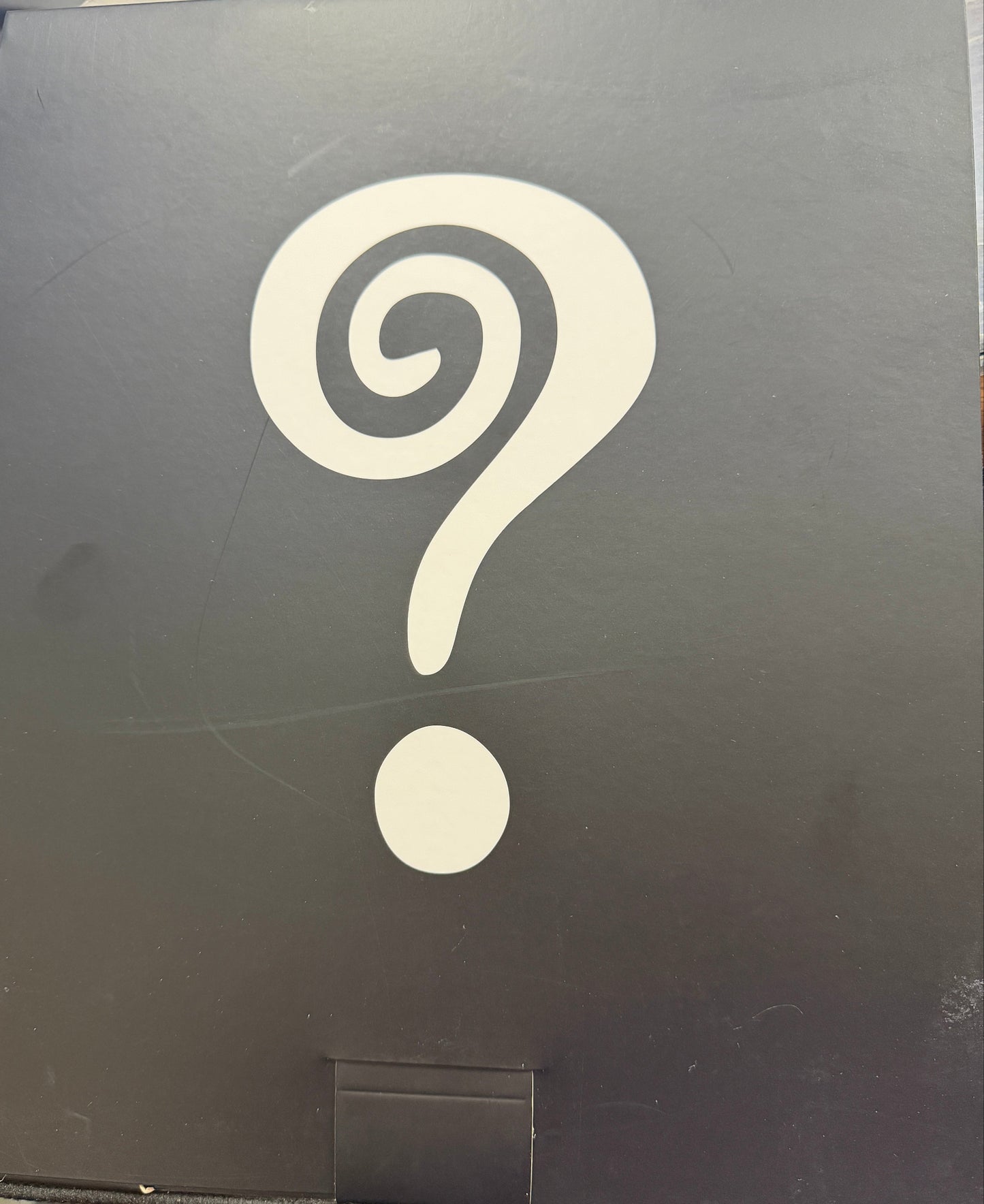 Black box with a white spiral design on a wooden surface