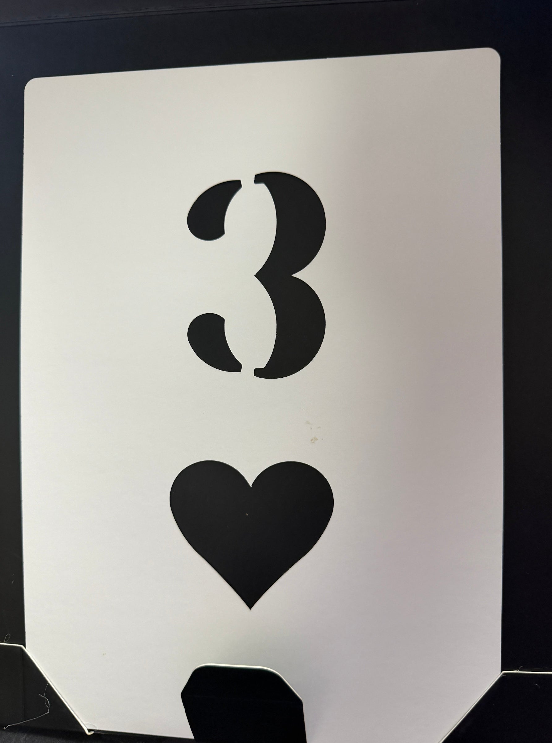 Stencils of a mustache and a heart on a white card with black border