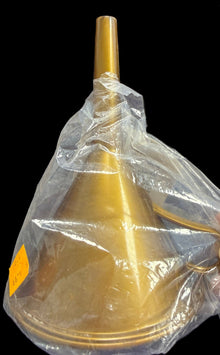 Gold funnel with a clear plastic bag over it, held by a hand on a dark surface.