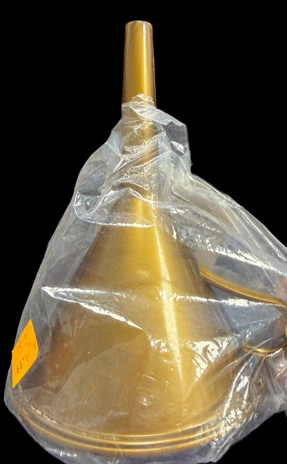 Gold funnel with a clear plastic bag over it, held by a hand on a dark surface.