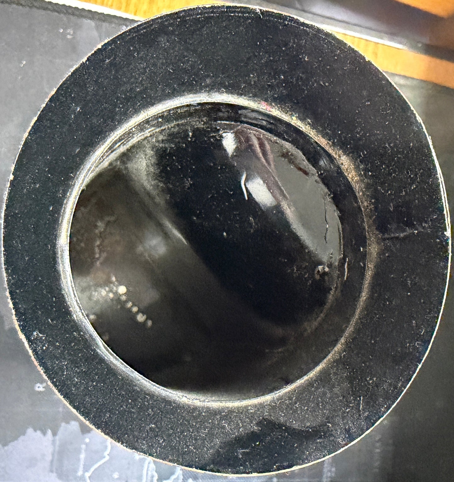 Close-up of a black circular object on a wooden surface with a map in the background.